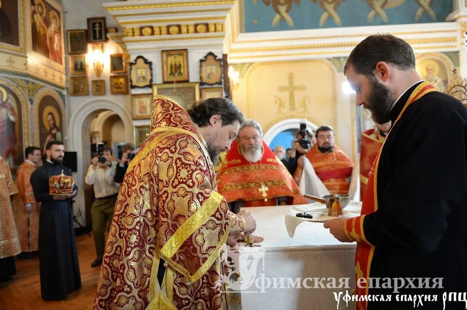 Патриарх Кирилл подписывает памятную книгу в присутствии духовенства
