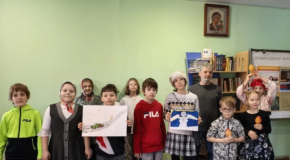 Дети из воскресной школы собора с рисунками и педагогом в классе
